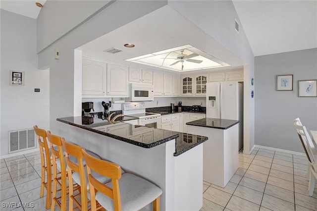 kitchen with white appliances, visible vents, a ceiling fan, and a peninsula