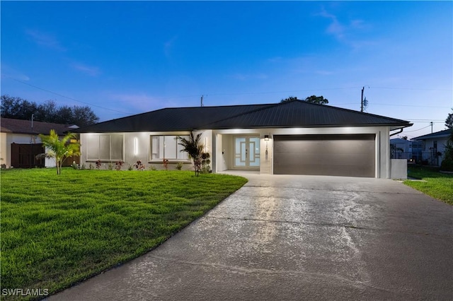 single story home with driveway, a garage, metal roof, a front lawn, and stucco siding