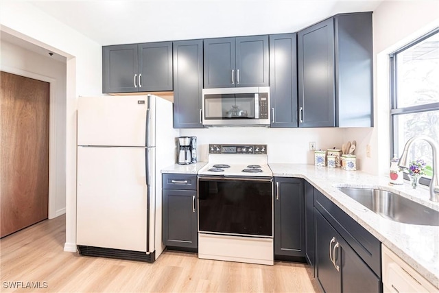 kitchen with sink, white refrigerator, light hardwood / wood-style floors, light stone counters, and electric stove