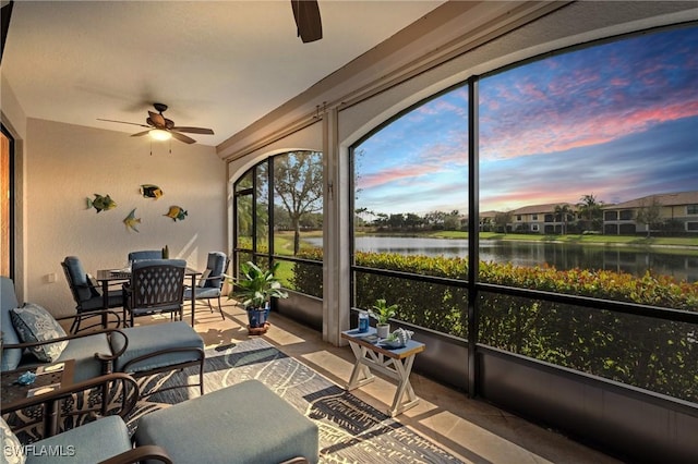 sunroom / solarium featuring ceiling fan and a water view