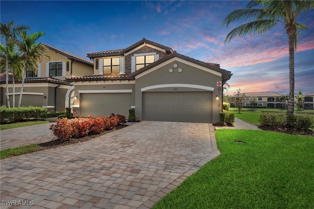 mediterranean / spanish house with stone siding, decorative driveway, and stucco siding