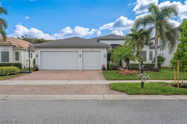 1813 Senegal Date Dr, Naples, FL 34119 - mediterranean / spanish house with decorative driveway, a tiled roof, stucco siding, an attached garage, and a front yard