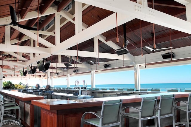 interior space with plenty of natural light, lofted ceiling with beams, and a water view