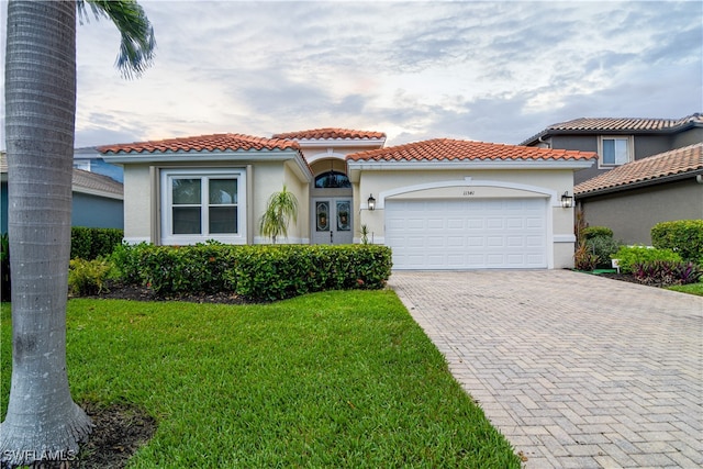 mediterranean / spanish home featuring a garage and a front lawn