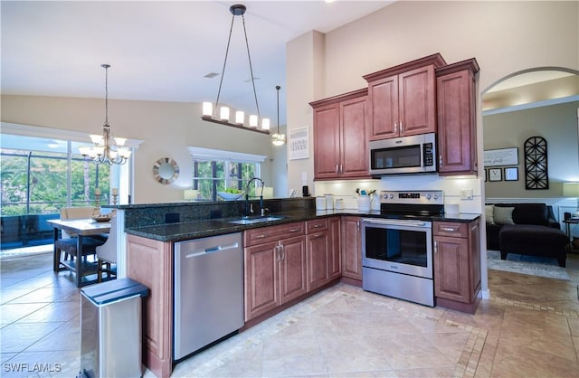 kitchen featuring dark stone countertops, sink, decorative light fixtures, and appliances with stainless steel finishes