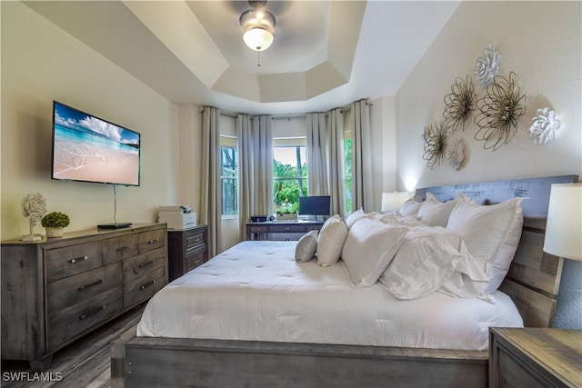 bedroom featuring dark hardwood / wood-style flooring, a tray ceiling, and ceiling fan