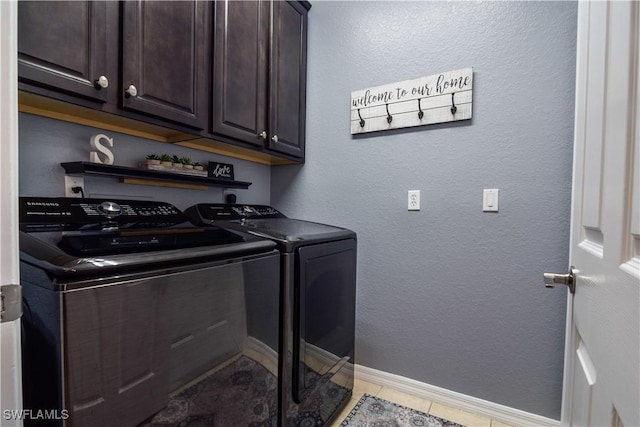 laundry area with light tile patterned floors, washing machine and dryer, and cabinets