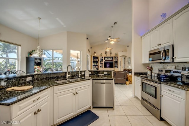 kitchen with decorative light fixtures, stainless steel appliances, open floor plan, white cabinetry, and a sink