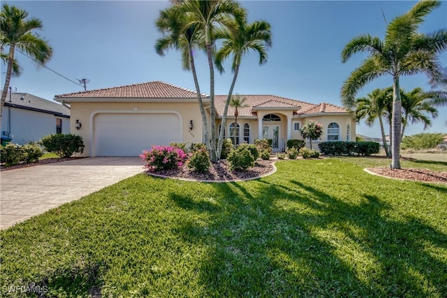 mediterranean / spanish home featuring a garage, a tile roof, decorative driveway, a front lawn, and stucco siding