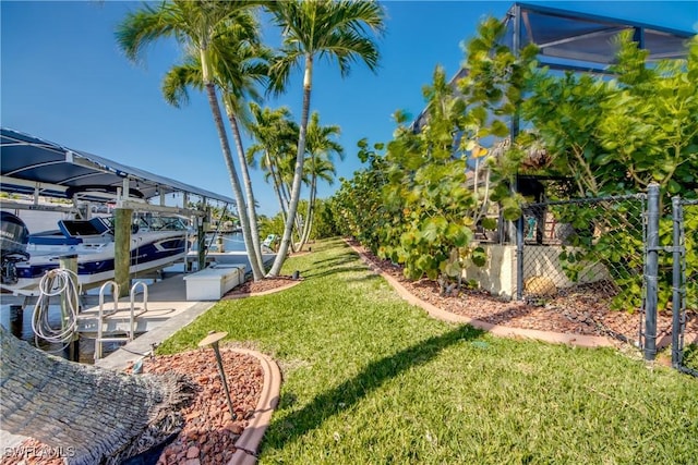 view of yard featuring a boat dock, boat lift, and fence