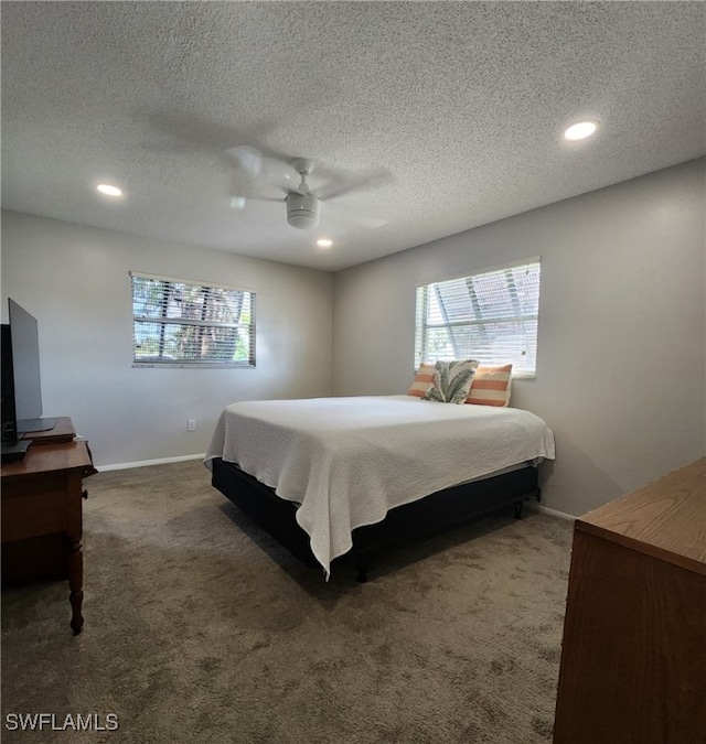 carpeted bedroom with a textured ceiling, multiple windows, baseboards, and a ceiling fan