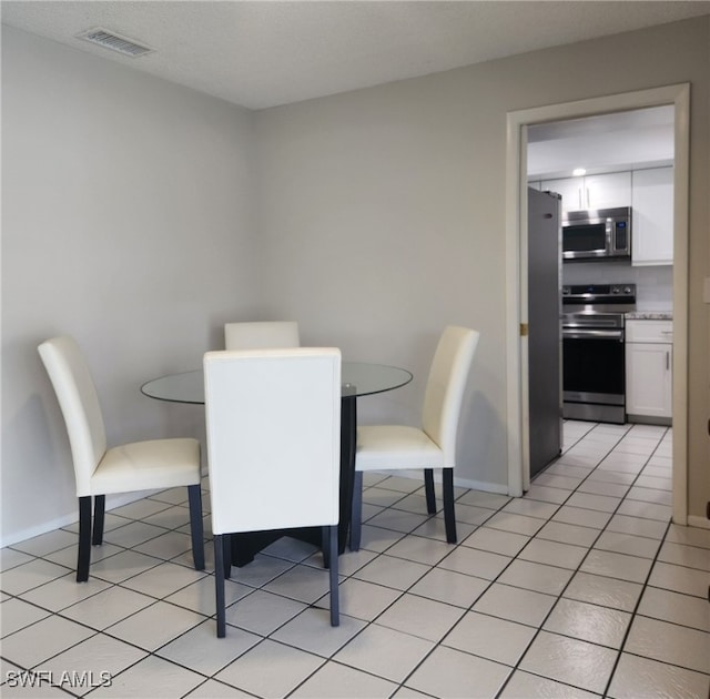 dining space featuring light tile patterned flooring, visible vents, and baseboards