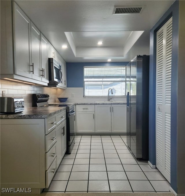 kitchen with stainless steel appliances, a raised ceiling, visible vents, decorative backsplash, and a sink