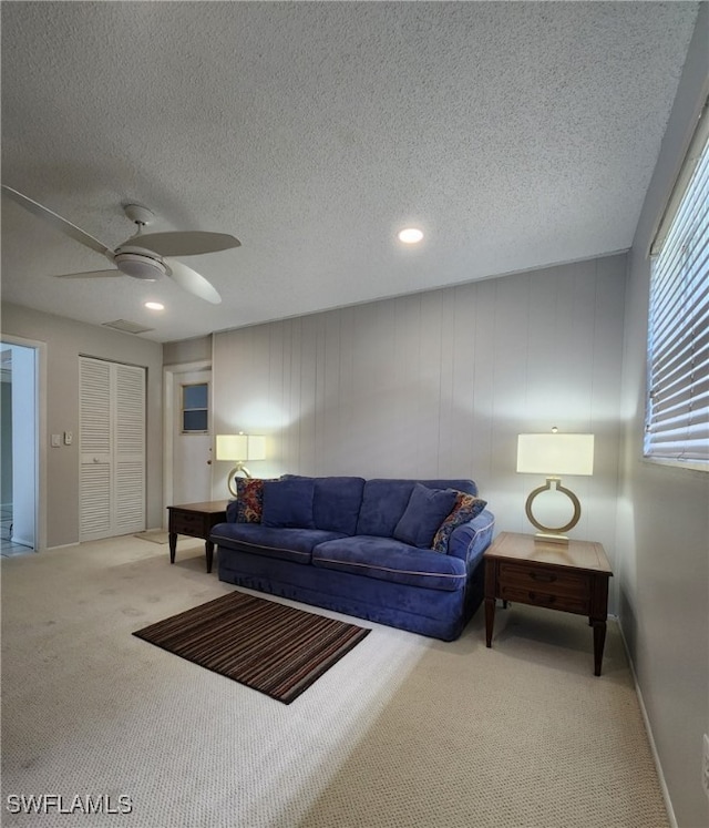 living room with ceiling fan, carpet floors, a textured ceiling, and baseboards