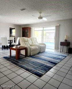 tiled living room featuring visible vents, ceiling fan, and a textured ceiling