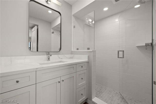 bathroom with a shower with shower door and vanity