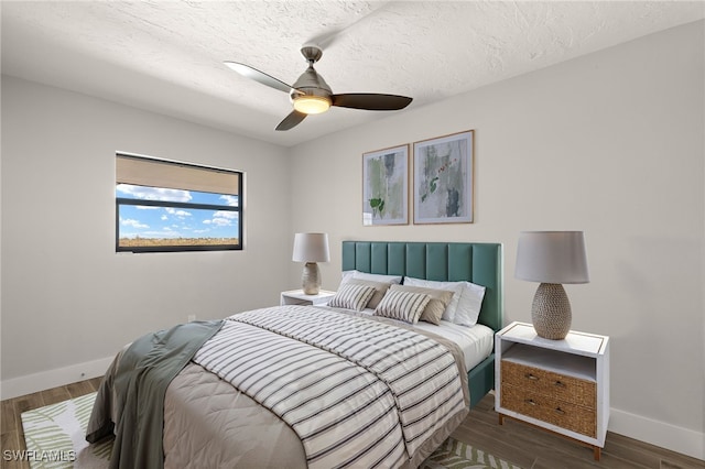 bedroom with ceiling fan, dark wood-type flooring, and a textured ceiling