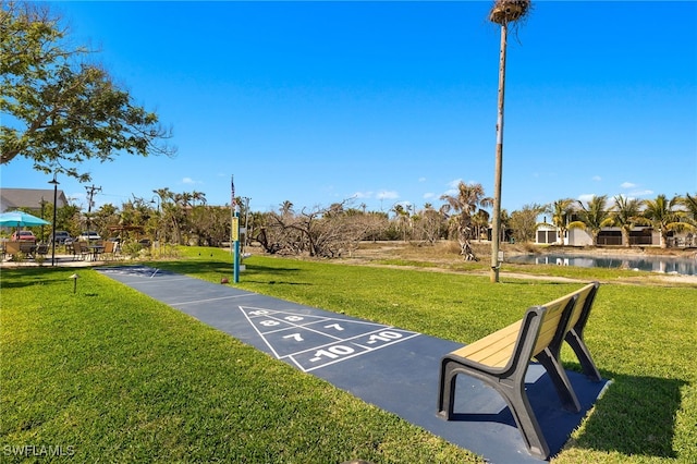 surrounding community with a water view and a lawn