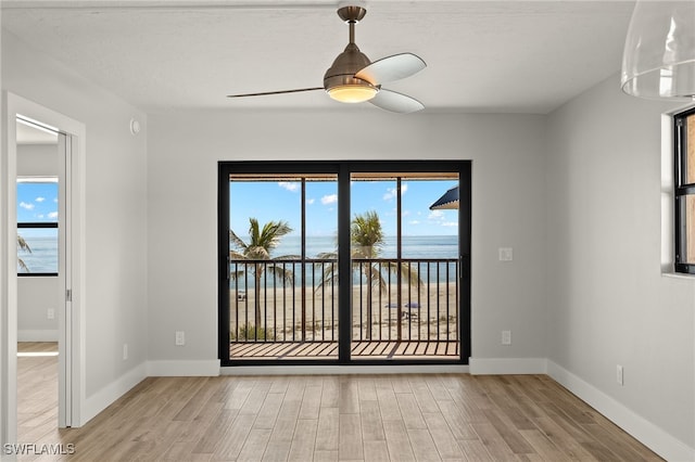 empty room featuring ceiling fan, a water view, and light wood-type flooring