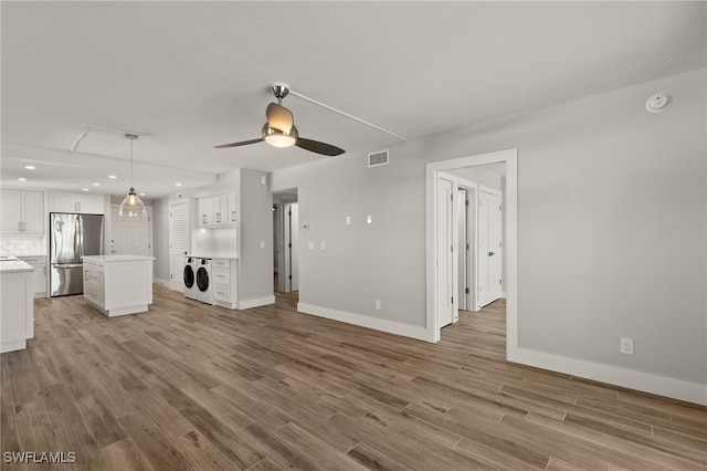 unfurnished living room with ceiling fan, light hardwood / wood-style floors, and washer / dryer