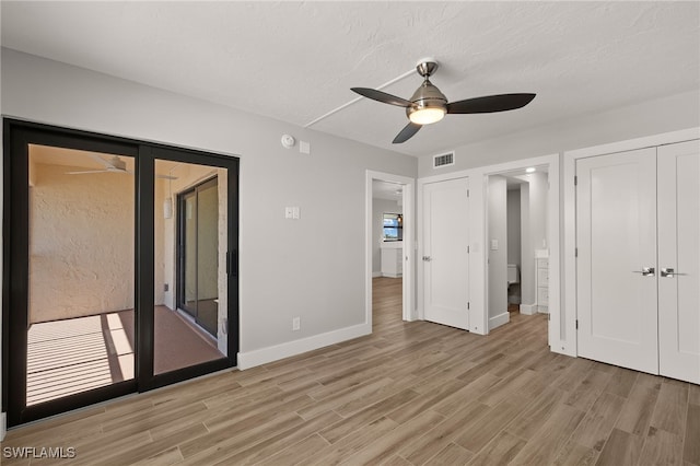 unfurnished bedroom featuring ceiling fan, light wood-type flooring, access to outside, and a textured ceiling