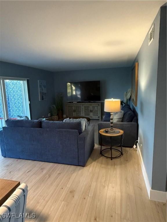 living area with baseboards, visible vents, and wood finished floors