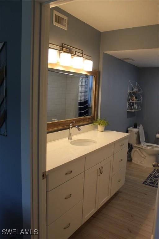 bathroom featuring toilet, visible vents, wood finished floors, and vanity