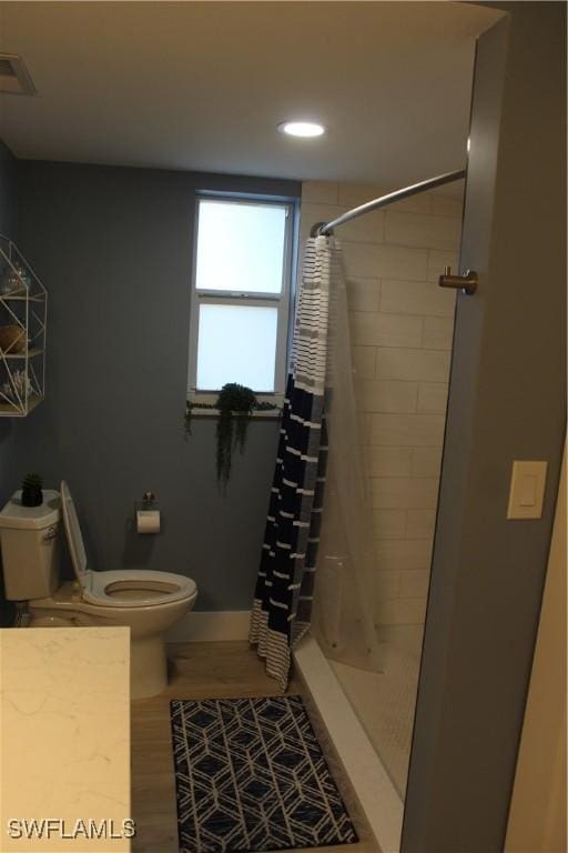 bathroom with visible vents, a shower with shower curtain, wood finished floors, and toilet