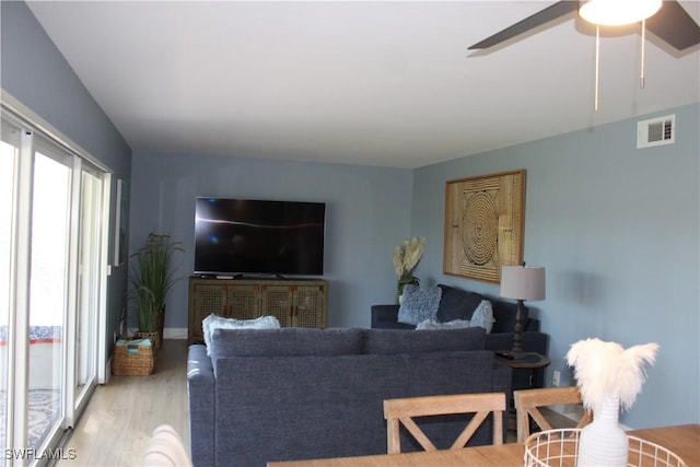 living room featuring wood finished floors, visible vents, and a ceiling fan