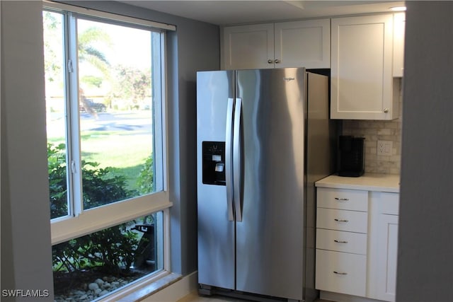 kitchen featuring light countertops, backsplash, stainless steel fridge, and white cabinetry