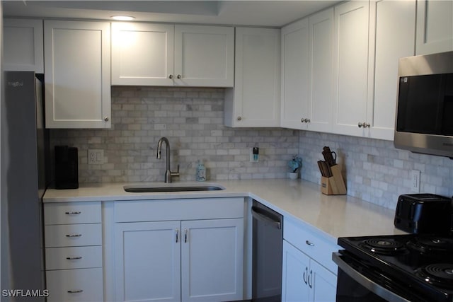 kitchen with a sink, white cabinetry, light countertops, appliances with stainless steel finishes, and backsplash