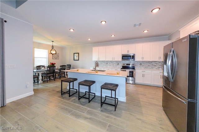 kitchen featuring white cabinets, stainless steel appliances, visible vents, and a sink