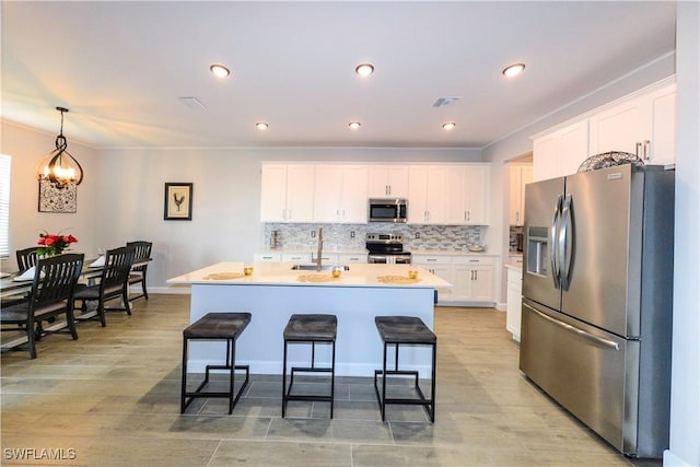 kitchen with a sink, stainless steel appliances, tasteful backsplash, visible vents, and white cabinetry