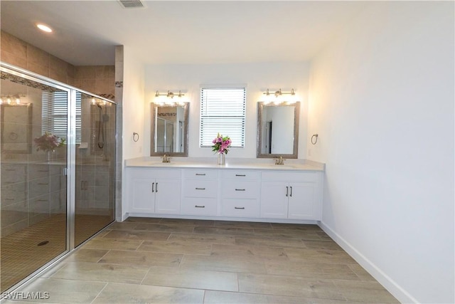 full bathroom with a stall shower, double vanity, and a sink