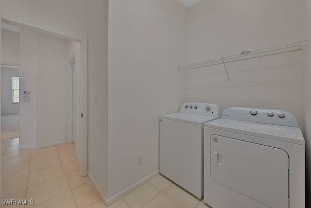 washroom with light tile patterned floors, laundry area, baseboards, and separate washer and dryer