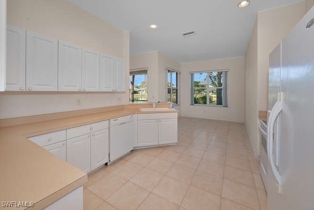 kitchen featuring a sink, white appliances, white cabinets, light countertops, and light tile patterned floors