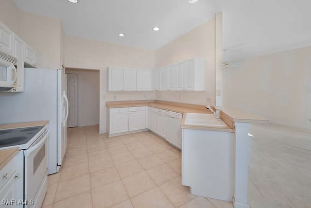 kitchen with light countertops, a peninsula, white appliances, white cabinetry, and a sink