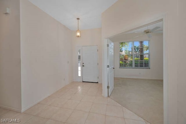 entrance foyer with light tile patterned floors, baseboards, light carpet, and ceiling fan