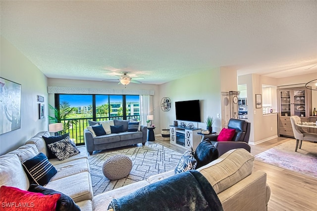 living room featuring a textured ceiling, wood finished floors, baseboards, and ceiling fan