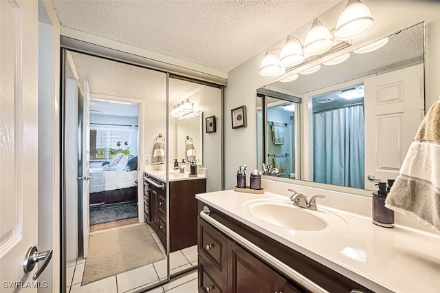 ensuite bathroom with a shower with shower curtain, two vanities, tile patterned floors, a textured ceiling, and a sink