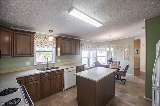 kitchen with sink, white appliances, hanging light fixtures, a center island, and a healthy amount of sunlight