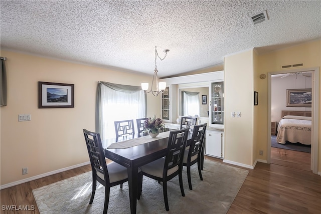 dining area with dark hardwood / wood-style floors, a textured ceiling, and a notable chandelier