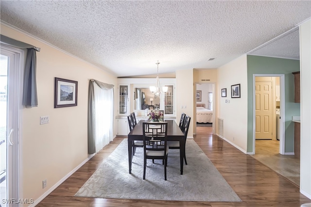 dining area featuring hardwood / wood-style flooring, lofted ceiling, a chandelier, and a textured ceiling