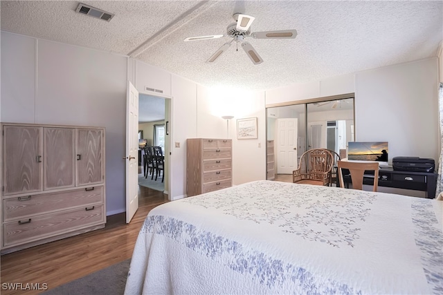 bedroom featuring ceiling fan, a textured ceiling, dark hardwood / wood-style flooring, and a closet