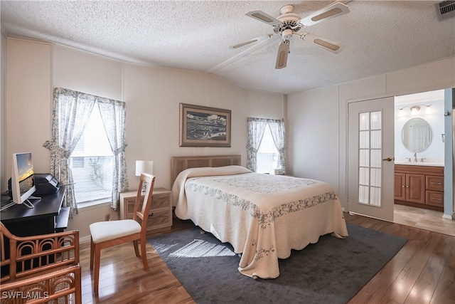 bedroom with lofted ceiling, hardwood / wood-style floors, a textured ceiling, and ceiling fan