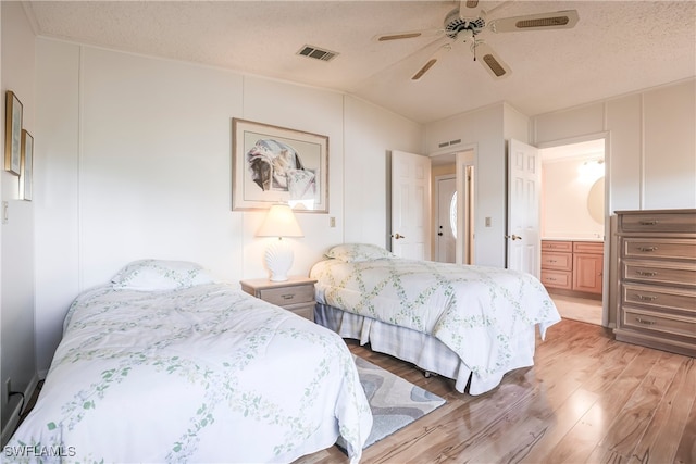 bedroom with vaulted ceiling, ceiling fan, light hardwood / wood-style floors, and a textured ceiling