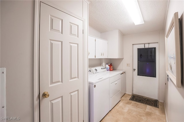 clothes washing area with independent washer and dryer, cabinets, and a textured ceiling