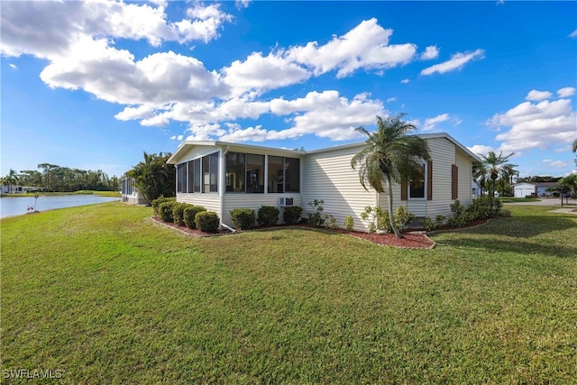 view of side of home with a lawn, a sunroom, and a water view