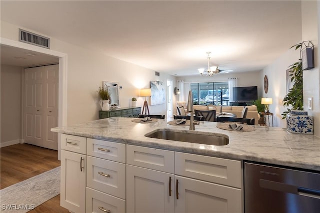 kitchen with visible vents, white cabinetry, a sink, light stone countertops, and dishwasher