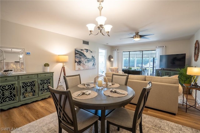 dining space with ceiling fan with notable chandelier, light wood-type flooring, and visible vents